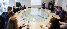 Teilnehmer*innen des EU-Kurs Frankfurt-Wiesbaden 2017 sitzen in einem Vortrag um einen Tisch mit einem Modell der Stadt Frankfurt in der Mitte