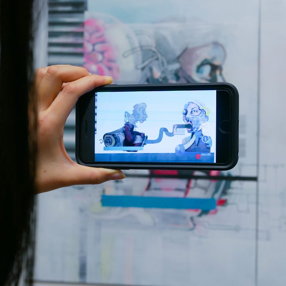 Eine Hand hält ein Smartphone vor ein Kunstwerk.