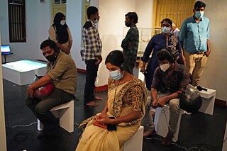 Visitors at the exhibition opening engaging with P. Ahilan's work "One & Many". 