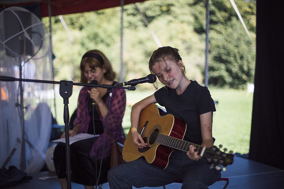 To unge mennesker sidder og spiller guitar og synger. 