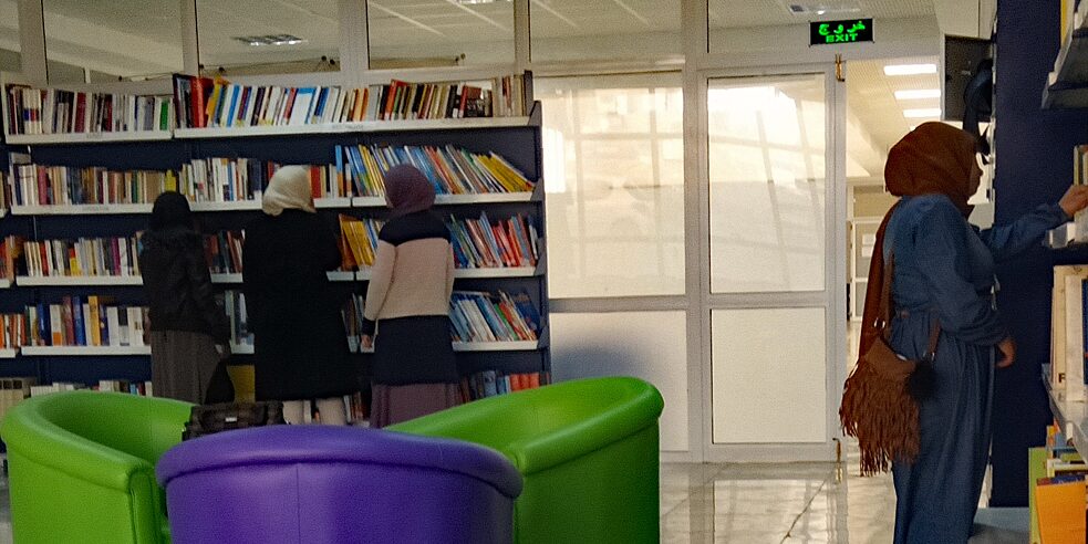 Etudiantes se placent devant des étagère à livres.