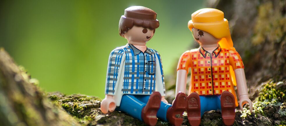 Spielfiguren-Paar sitzt in der Natur