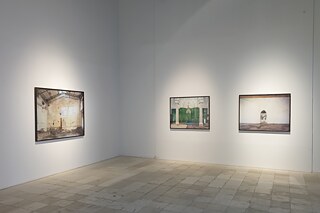 An einer Ausstellungswand hängen drei gerahmte Fotografien, die Orte der Religionsausübung zeigen.