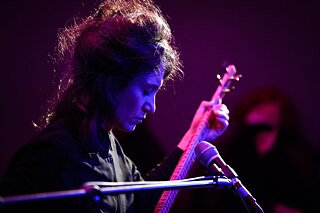 Die Musikerin Elshan Ghasimi spielt mit geschlossenen Augen auf der Langhalslaute Tar. 