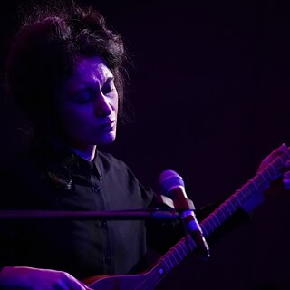 Die Musikerin Sldhan Ghasimi spielt mit geschlossenen Augen auf der Langhalslaute Tar. 