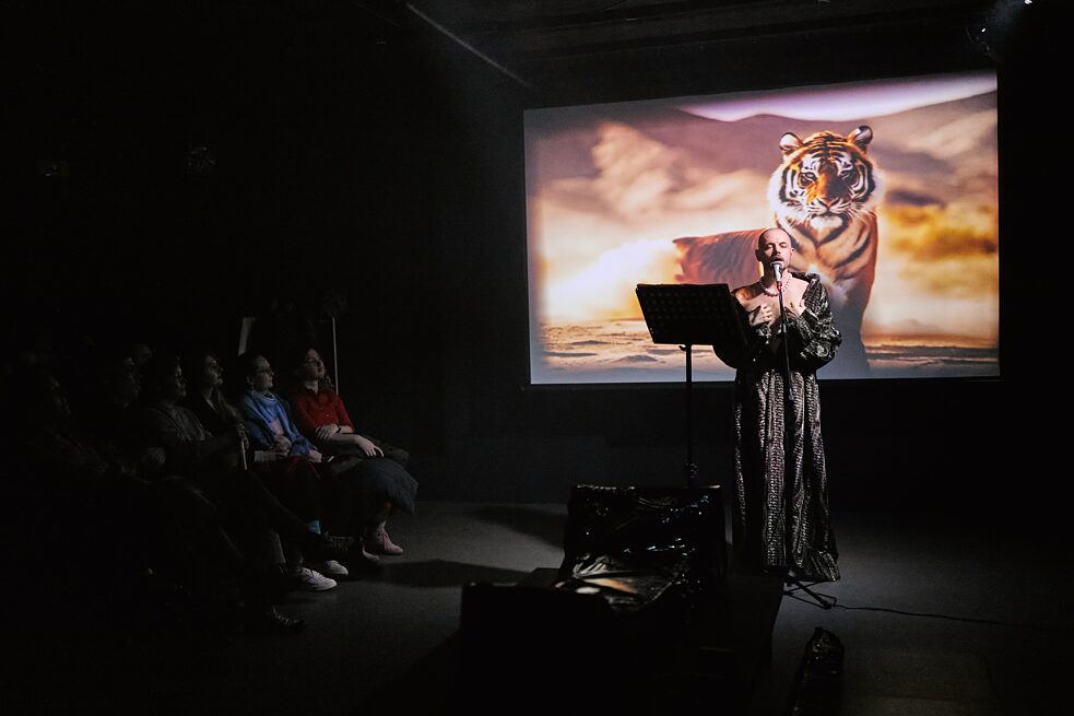 Mann im Theater vor einer Projektion mit einem Tiger
