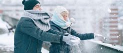 Zwei junge Menschen mit Mützen und Schals halten Schnee in den Händen.