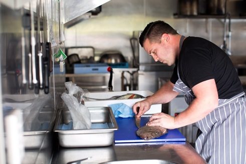Chefkoch Logan Coath filetiert einen Petersfisch in der Küche des Archive 