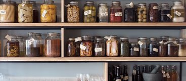 A wall of preserves and pickles line the wall in the restaurant 