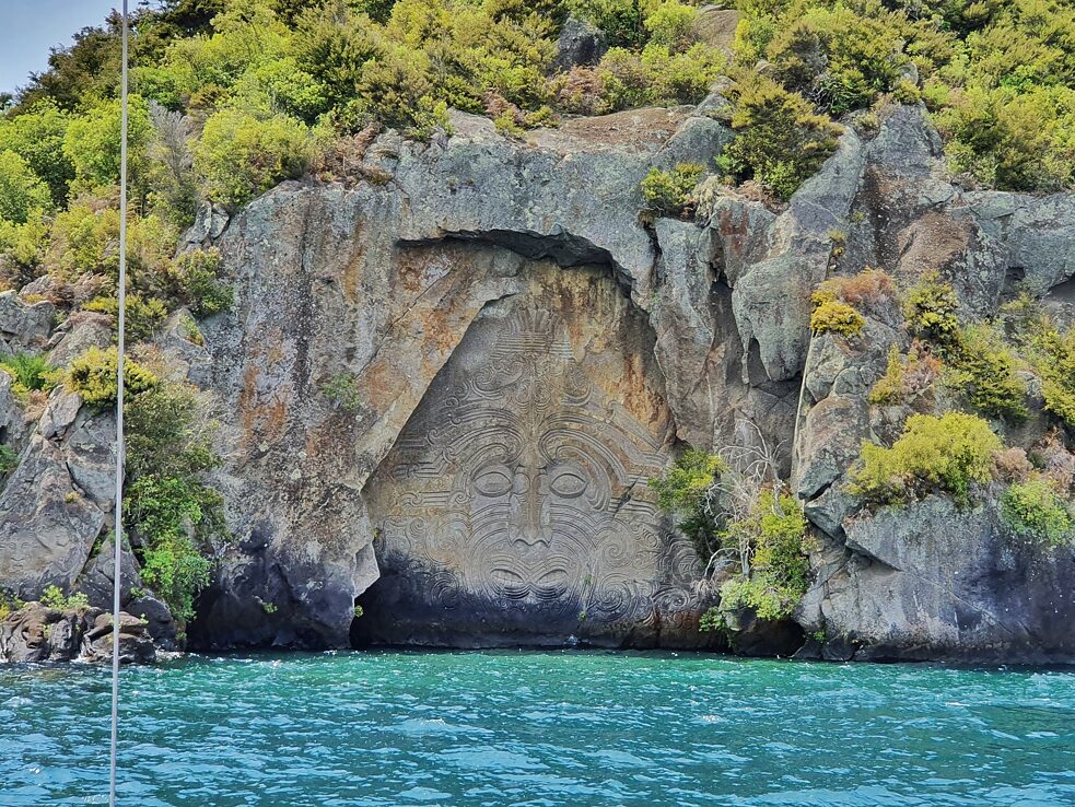 Maori Rock Carving - Die 14 Meter hohe Skulptur in Mine Bay; beim Betrachten der Schnitzereien liefern die Fremdenführer*innen eine Menge Hintergrundinformationen, damit man ihre Bedeutung versteht.