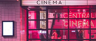 Exterior view of a pink illuminated cinema.
