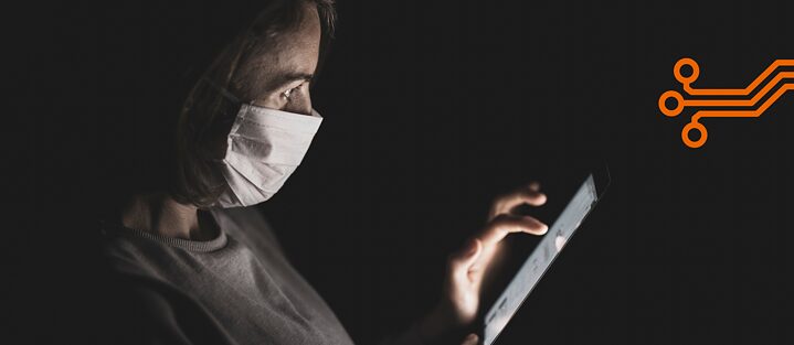 A woman with a mask looks at her smartphone.