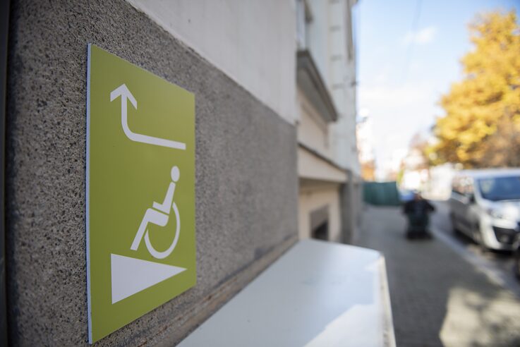 Табела на ъгъла на сграда с изобразена рампа за хора с увреждания.