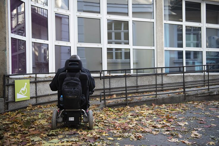 Mann im Rollstuhl vor einer Rollstuhlrampe
