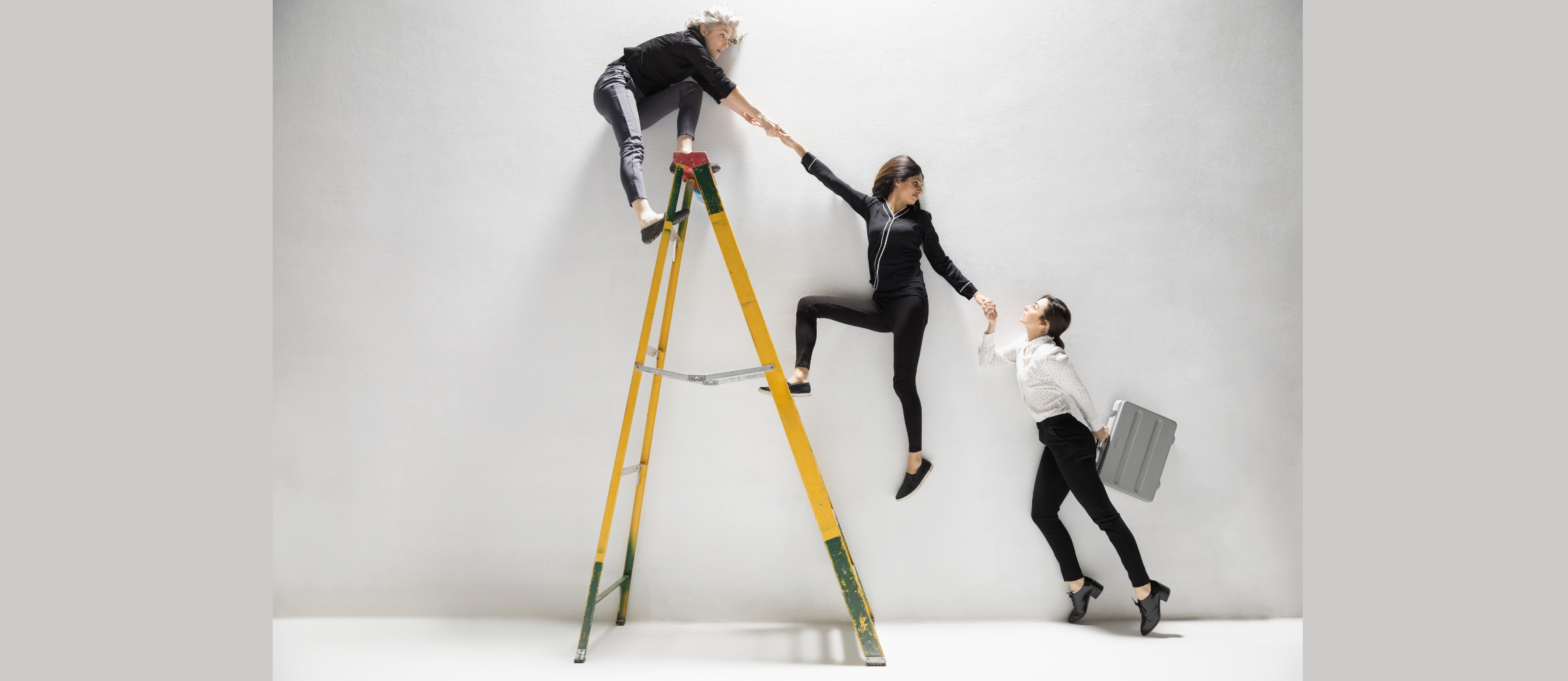 Trois femmes d'affaires s'aident mutuellement à grimper une échelle.