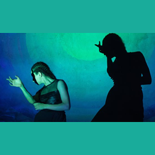 Foto einer tanzenden Person vor einem blau und grün beleuchteten Hintergrund