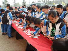 Schülerinnen und Schüler der Yueyang Fremdsprachenschule unterschreiben auf dem Werbebanner zum Umweltschuzt.