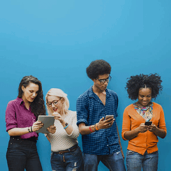 Vor einem blauen Hintergrund schauen 4 junge Menschen gemeinsam auf ihre Handys und Tabltes