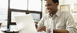 Young man sitting at a desk, typing on a laptop.