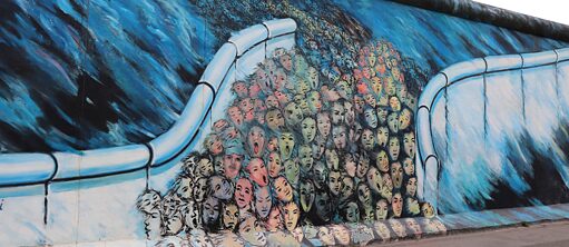 Berliner Mauer Graffiti, das Bild zeigt geöffnete Wand und vielen Gesichten