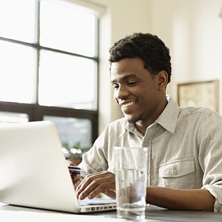Young man sitting at a desk, typing on a laptop.