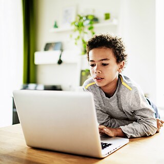 صبي في المرحلة الابتدائية يَنصب تركيزه على جهاز لاب توب أمامه.