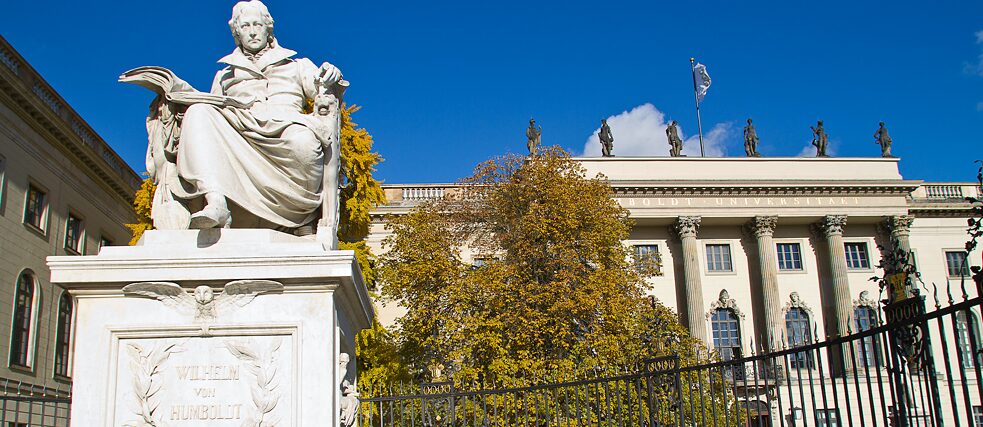 Die Humboldt-Universität in der Straße Unter den Linden im Bezirk Mitte. Im Vordergrund steht die Statue Wilhelm von Humboldt.