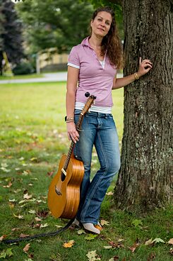 Antje Duvekot leaning against a tree with guitar