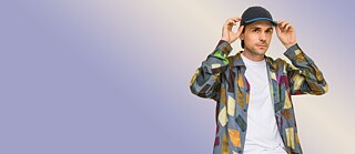 Der Autor Leif Randt steht vor einem violetten Hintergrund.