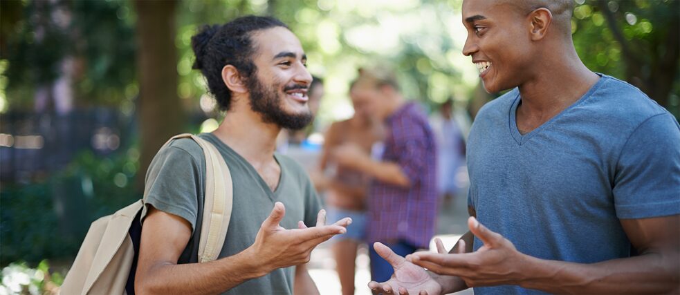 Zwei junge Männer reden miteinander auf der Straße.