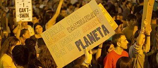 Uma manifestação com um cartaz que diz: „Por quê terminar a escola se estamos a destruir o planeta?“  
