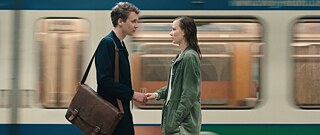 Relativity - teaser image: a man and a woman meet on a platform at a train station