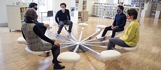 Fünf Personen sitzen auf einem runden Sitz in der Bibliothek