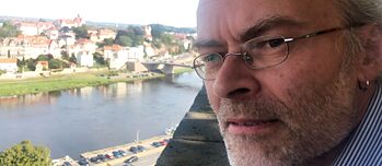 Den danske filosof Peter Tudvad står på en bro i den tyske by Meissen, i baggrunden ses byen.