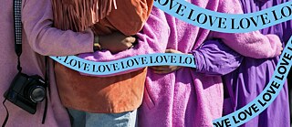 Close-up of people from behind who are embracing each other, lettering love all over the place