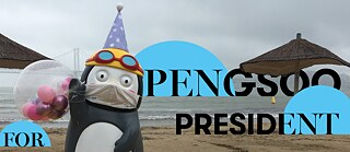 Eine große Pinguinfigur aus Plastik mit Mundschutz an einem Strand