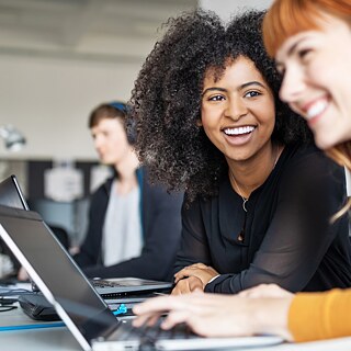 Zwei lachende Frauen vor einem Laptop