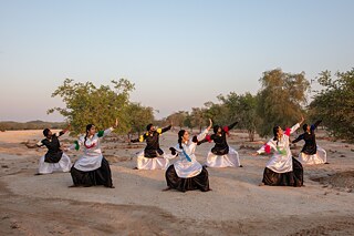 أعضاء فرقة "بالي بالي" للرقص في دبي يؤدون رقصة "بانجرا" في منطقة "القدرة" الصحراوية بدبي. يستضيف أعضاء الفرقة ورش عمل مفتوحة ومتاحة للجميع وذلك في صباح كل يوم جمعة أثناء أشهر الشتاء، كما يقدمون رقصات بشكل منتظم في مختلف الأماكن العامة في دبي، من مواقف سيارات وحدائق وشواطئ.