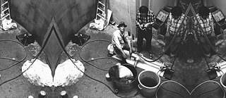 Profesor Joseph Beuys při práci na instalaci “ArtHoney” během festivalu documenta 6 v Kasselu. Dílo obsahovalo tekutinu podobnou medu, která kolovala v trubkách. Pořízeno 19. června 1977.