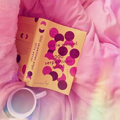 Bogen 1000 Serpentinen Angst ligger på en seng, til venstre kan ses en kop kaffe.