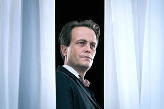 Stillframe from the series “Bauhaus - A new Era": August Diehl as Walter Gropius looking between two curtains