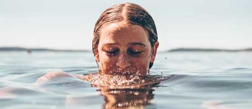 Das Gesicht eines Mädchens, das in Wasser getaucht ist und lächelt