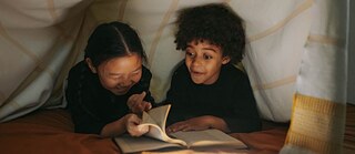 Zwei Kinder lesen ein Buch.