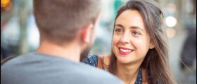 A young man and a young woman greet each other. 