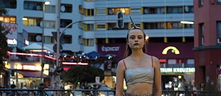 A girl with a unicorn headband stands in front of a Berlin-Kreuzberg apartment complex