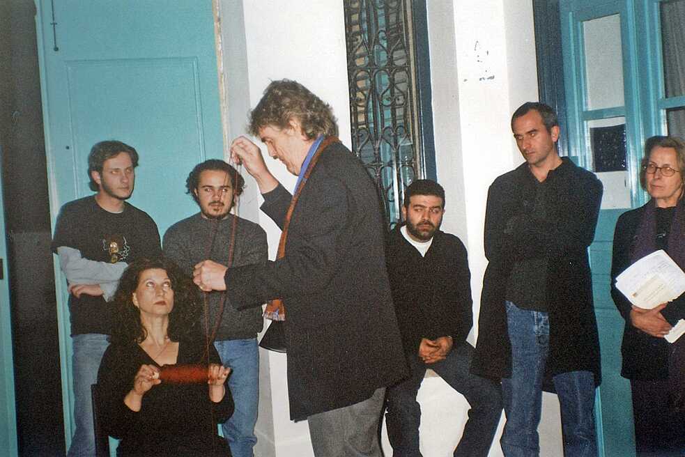 Ο καλλιτέχνης Horst Weierstall παρουσιάζει μια αφηρημένη εγκατάσταση σε ένα κοινό. Το βλέμμα του επικεντρώνεται στο αντικείμενο που έχει στα χέρια του. Φοράει ένα κομψό μαύρο κοστούμι με παντελόνι καφέ. Οι έξι θεατές στέκονται μπροστά από μια τυρκουάζ πόρτα και ένα παράθυρο με τιρκουάζ πλαίσιο και κοιτάζουν προσεκτικά τον καλλιτέχνη.
