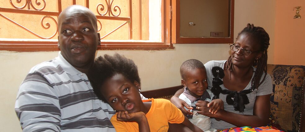 Die Familie Sama sitzt zusammen auf dem Sofa