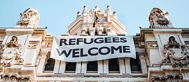 Transparent an der Fassade des Madrider Rathauses mit der Aufschrifft „Refugees Welcome“
