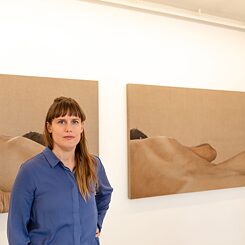 The artist Caroline Thon in front of two of her paintings.