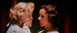 The two main characters from the film "Aimee & Jaguar", Lily (blonde, on the left) and Felice (brunette, on the right) are standing facing each other.